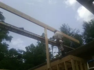 Carpenter setting a ridge beam over a new addition frame — Ice Dam Removal by Roofing Brothers in Wilson Creek
