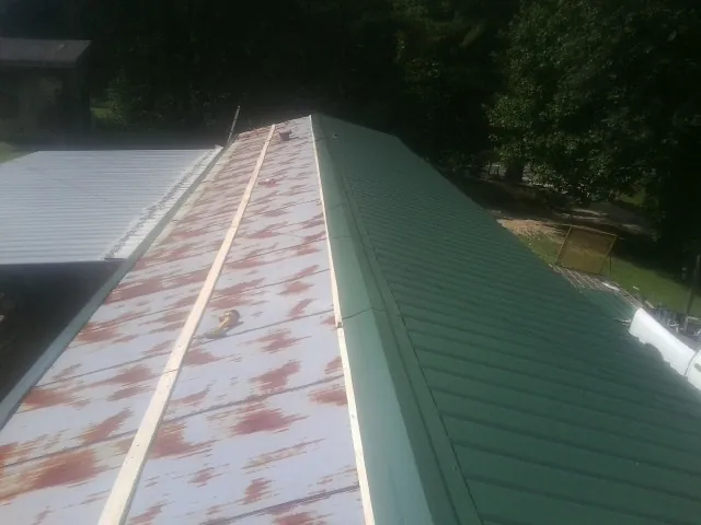 Old rusted panels beside newly installed green metal roofing — Wind Damage Roof Repair by Roofing Brothers in Wilson Creek