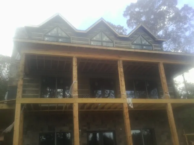 Dormers and porch framing on a large log home under construction — Roof Coating work by our crew in Wilson Creek