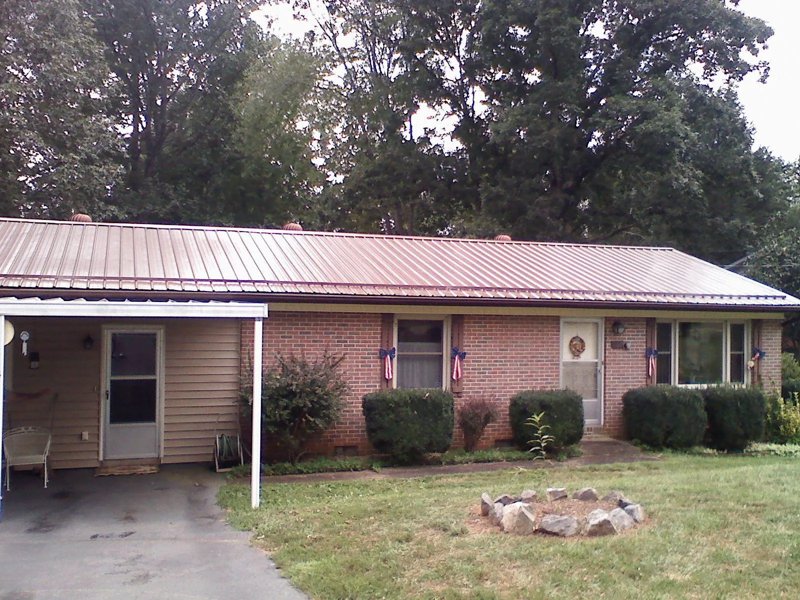 Bronze metal roof and carport on a brick ranch home — Roof Repair work by our crew in Wilson Creek