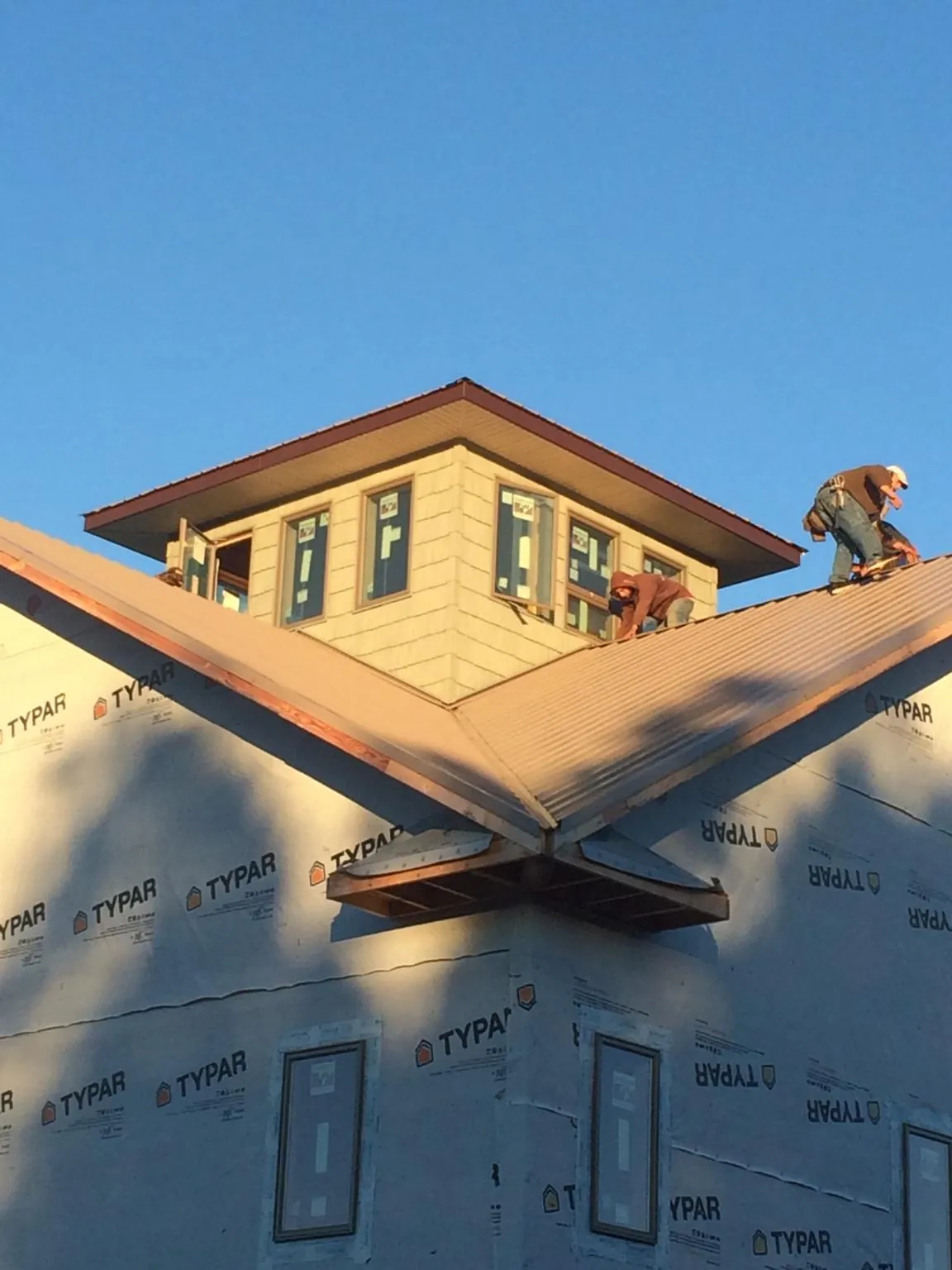 Roofers working around a rooftop cupola on a new metal roof at sunset — Roof Waterproofing in Wilson Creek by Roofing Brothers